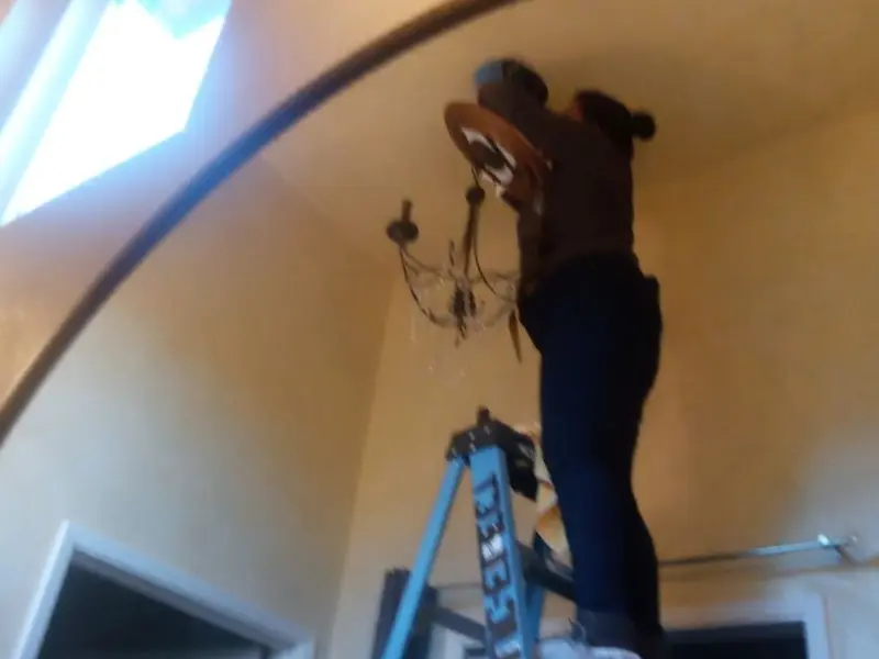 Electrician installing a chandelier in a Wayne residence